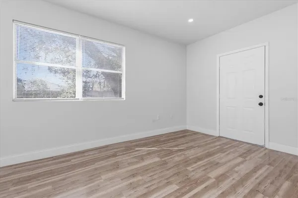 a view of empty room with wooden floor and fan