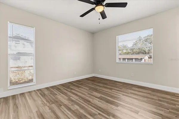 a view of empty room with wooden floor and fan