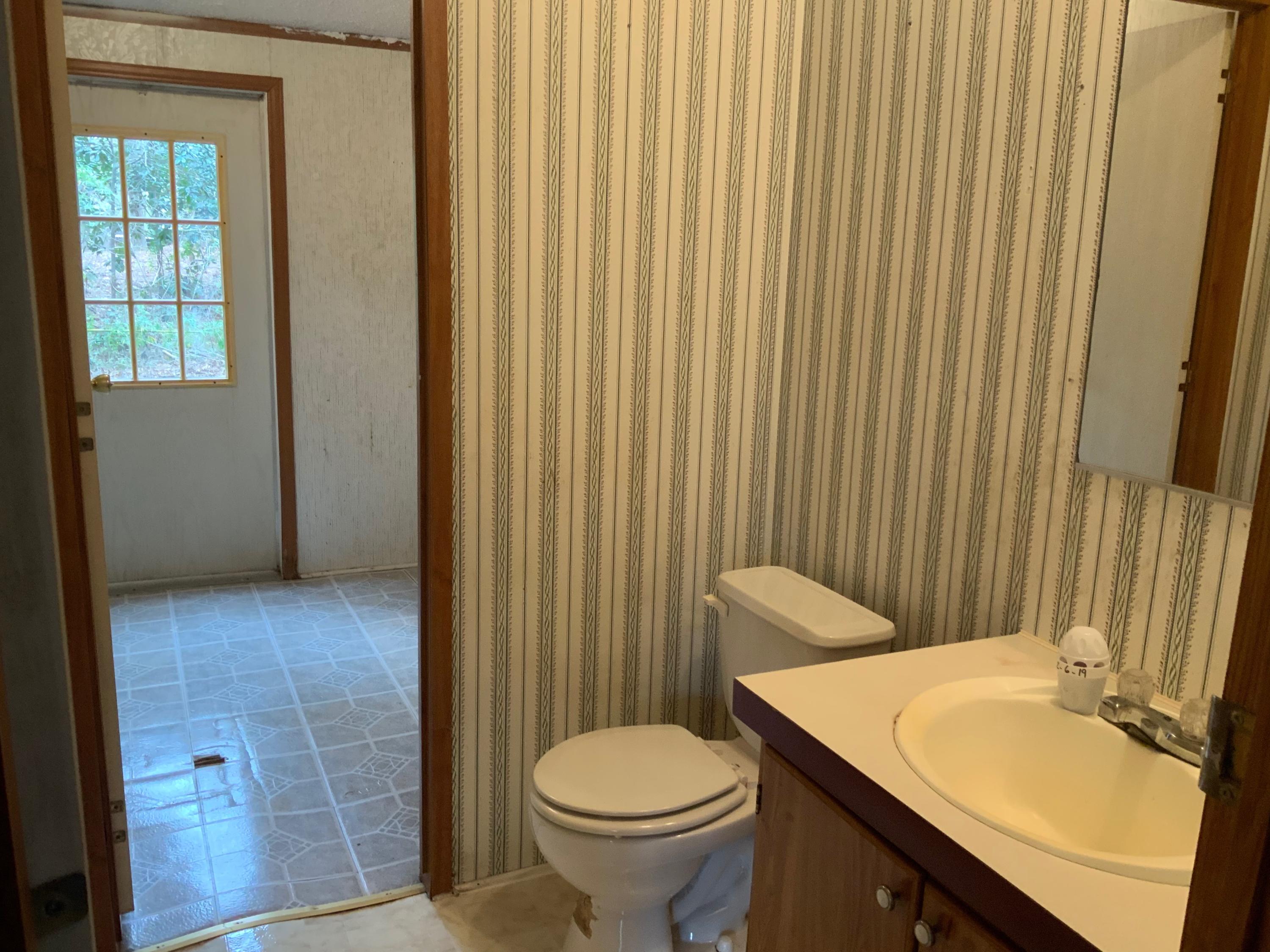 126 South 3rd Street Santa Rosa Beach, FL 32459 - Photo 12 of 12 a bathroom with a granite countertop toilet a sink and a mirror