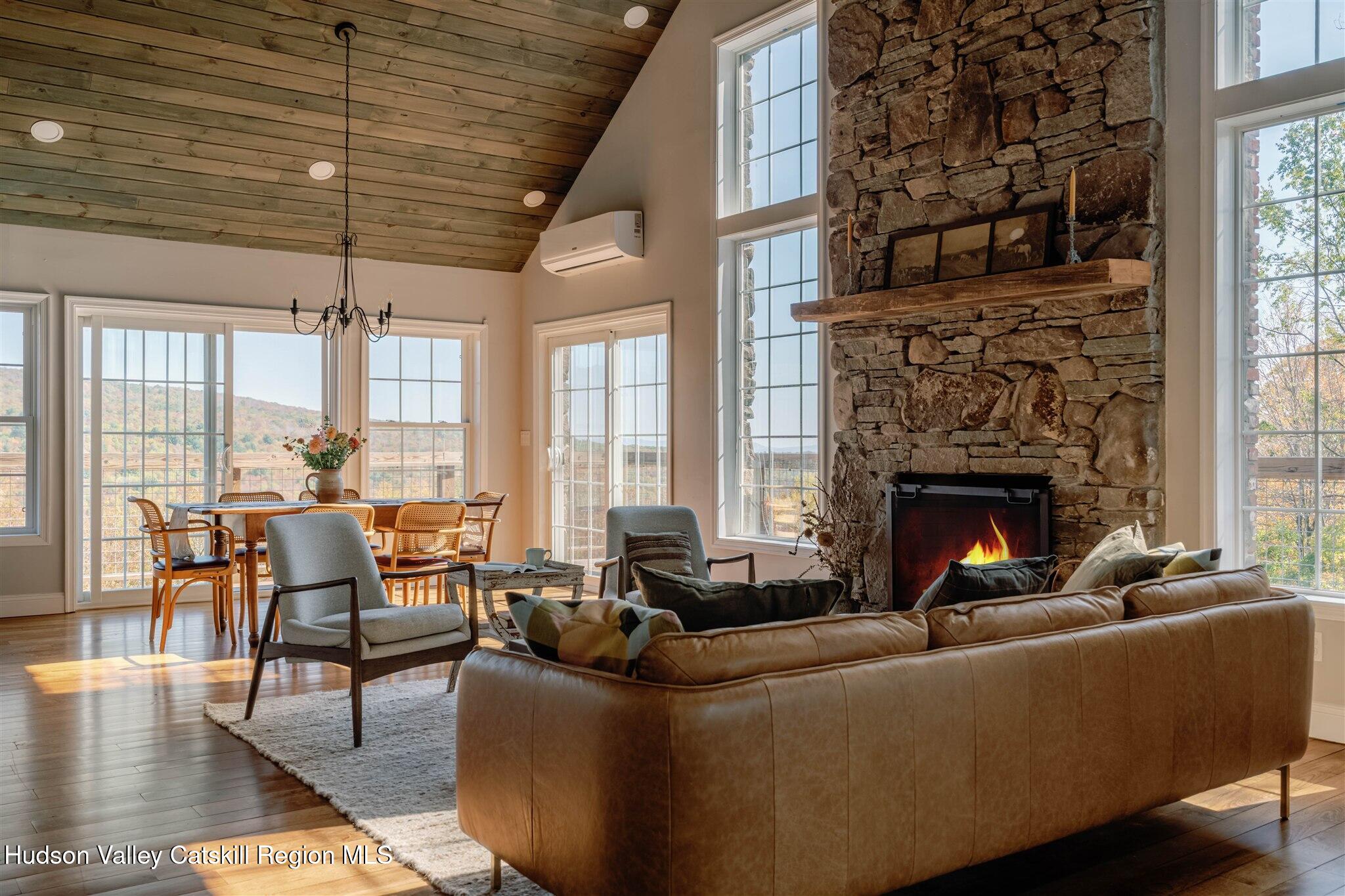 321 Mutton Hill Road Neversink, NY 12765 - Photo 3 of 25 a living room with furniture a fireplace and floor to ceiling windows