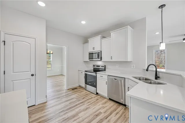 a large kitchen with stainless steel appliances granite countertop a sink a stove and a wooden floors