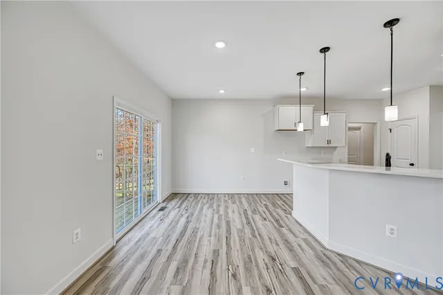 a large kitchen with stainless steel appliances granite countertop a stove a sink a refrigerator and white cabinets with wooden floor