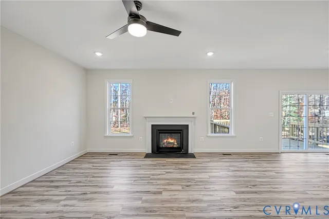 an empty room with wooden floor fireplace and windows