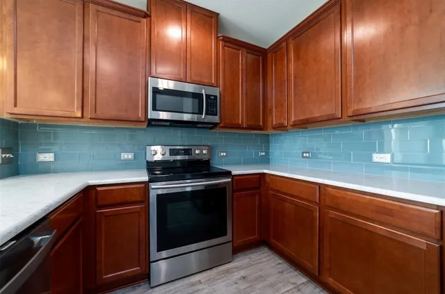 a kitchen with stainless steel appliances kitchen island granite countertop wooden floors wooden cabinets and sink