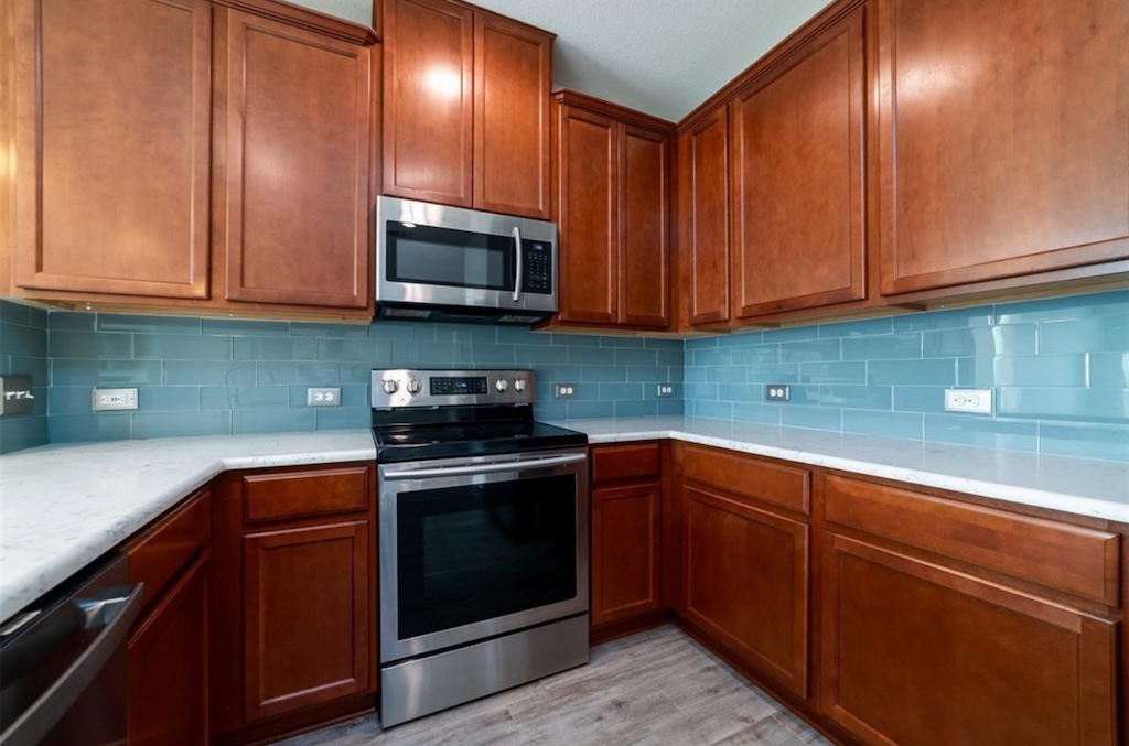 7013 Lickeen Court Austin, TX 78744 - Photo 2 of 20 a kitchen with stainless steel appliances granite countertop wooden cabinets a stove a sink and dishwasher