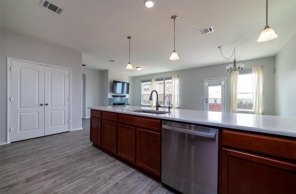 7013 Lickeen Court Austin, TX 78744 - Photo 19 of 20 a large kitchen with kitchen island white cabinets and wooden floor