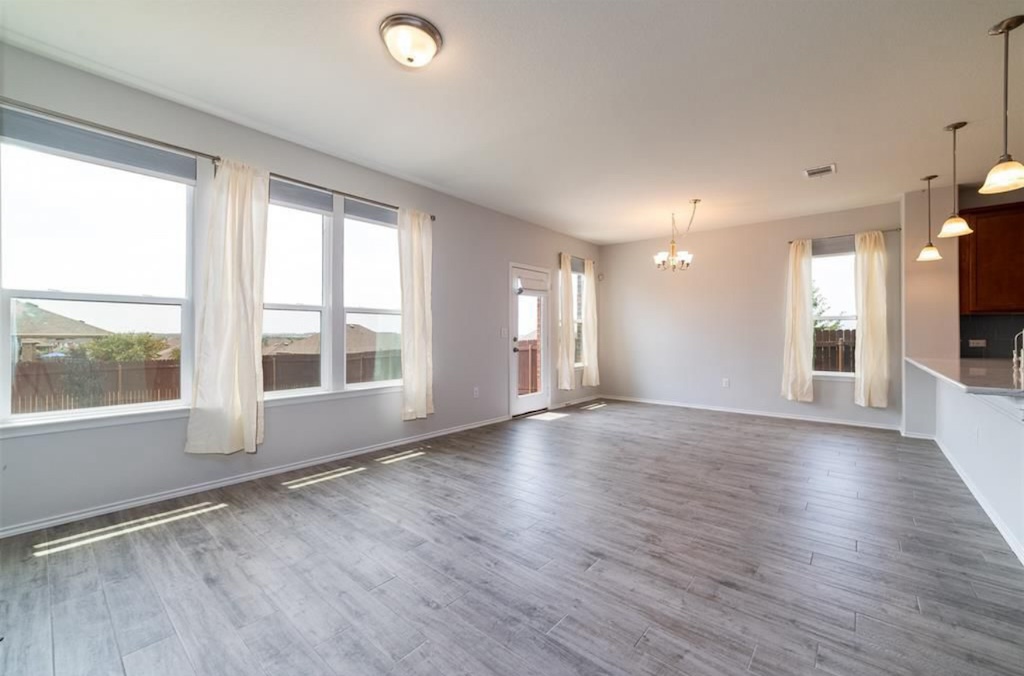 7013 Lickeen Court Austin, TX 78744 - Photo 4 of 20 a view of an empty room with a window and wooden floor