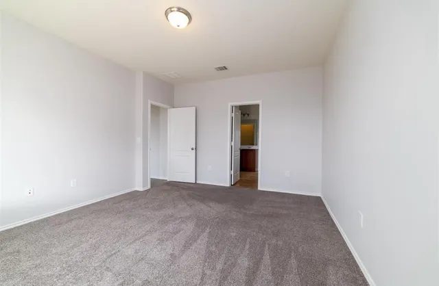 a view of an empty room with kitchen and window