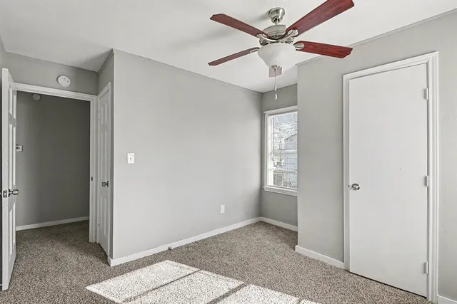 a view of an empty room with closet and a ceiling fan
