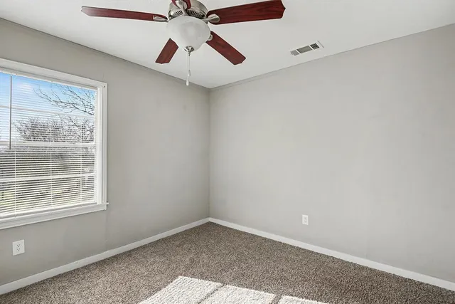 an empty room with a window and a fan