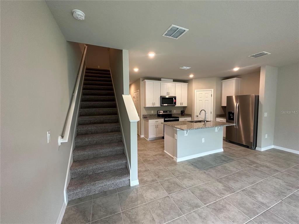 430 Legacy Loop Davenport, FL 33896 - Photo 12 of 21 a large kitchen with stainless steel appliances kitchen island granite countertop a refrigerator and a sink