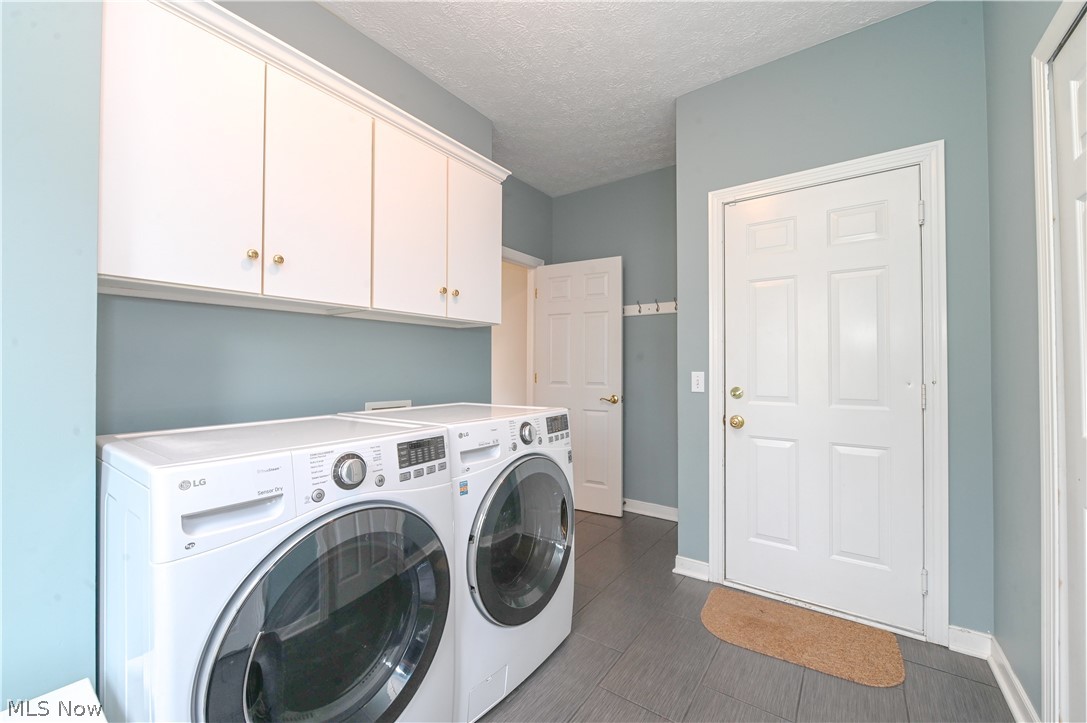1688 Sheridan Road South Euclid, OH 44121 - Photo 38 of 48 Clothes washing area featuring dark tile flooring, washing machine and dryer, cabinets, and a textured ceiling