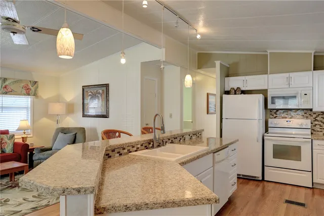 a kitchen with kitchen island granite countertop a sink appliances cabinets and furniture