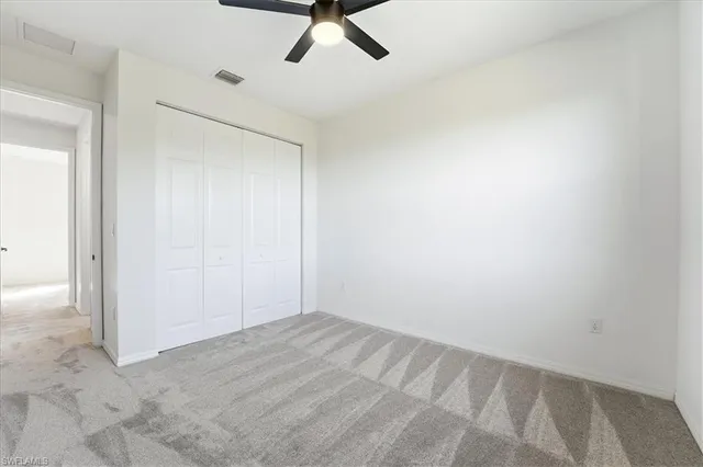 an empty room with a ceiling fan and carpet