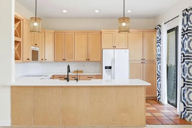 a kitchen with granite countertop a refrigerator a sink and white cabinets