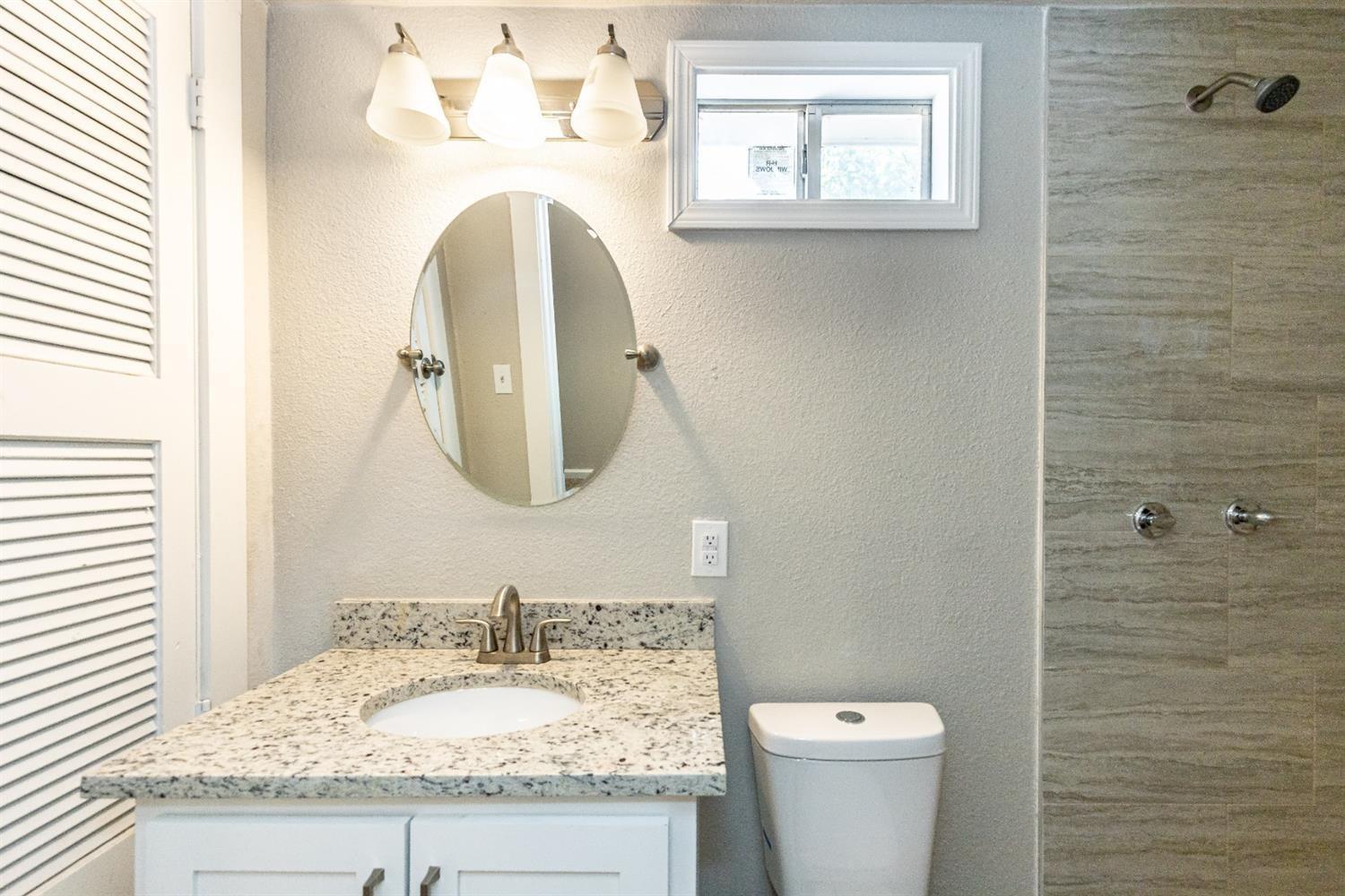 2723 66th Street Lubbock, TX 79413 - Photo 14 of 17 a bathroom with a granite countertop toilet sink and mirror