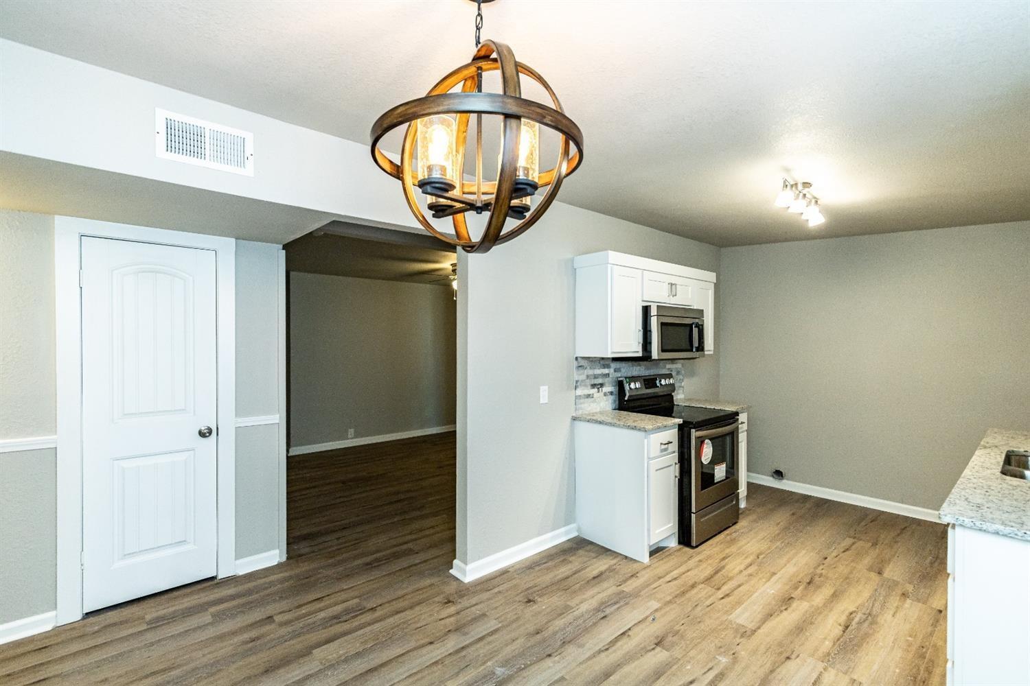 2723 66th Street Lubbock, TX 79413 - Photo 6 of 17 a kitchen with granite countertop stainless steel appliances and wooden floor