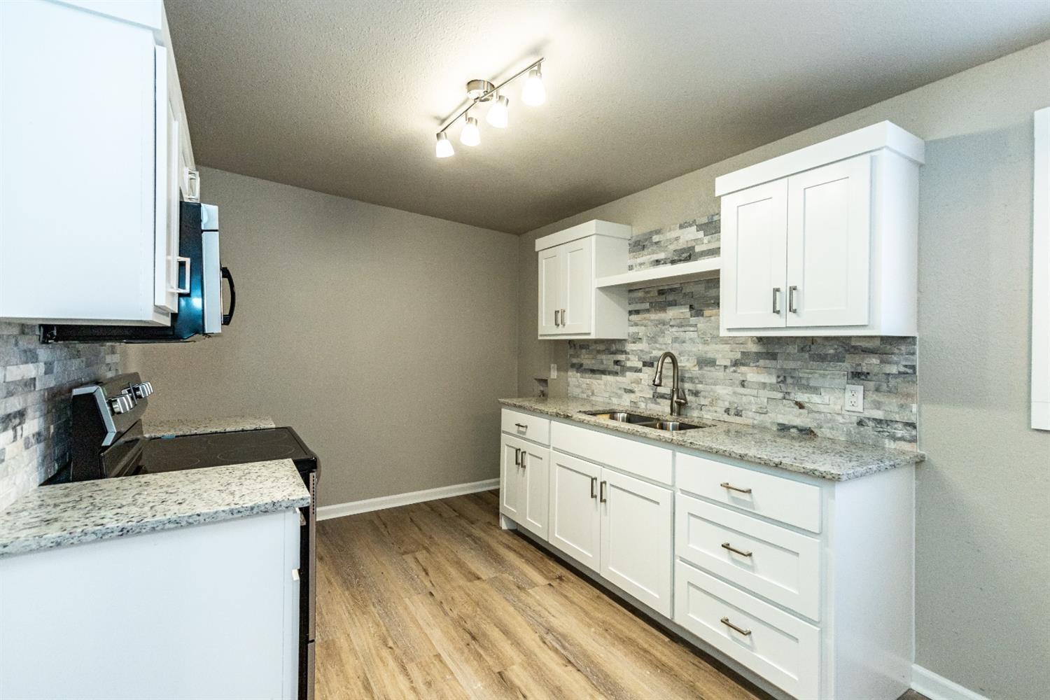 2723 66th Street Lubbock, TX 79413 - Photo 8 of 17 a kitchen with granite countertop white cabinets and white appliances