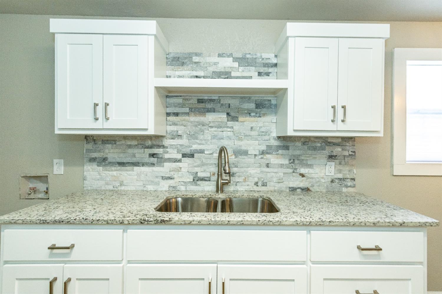 2723 66th Street Lubbock, TX 79413 - Photo 9 of 17 a kitchen with granite countertop a sink and cabinets