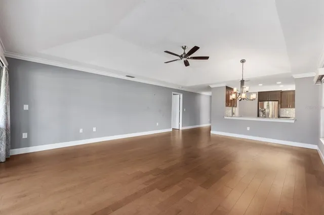 a view of an empty room with window and wooden floor
