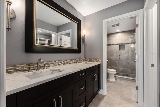 a bathroom with a double vanity sink toilet and shower