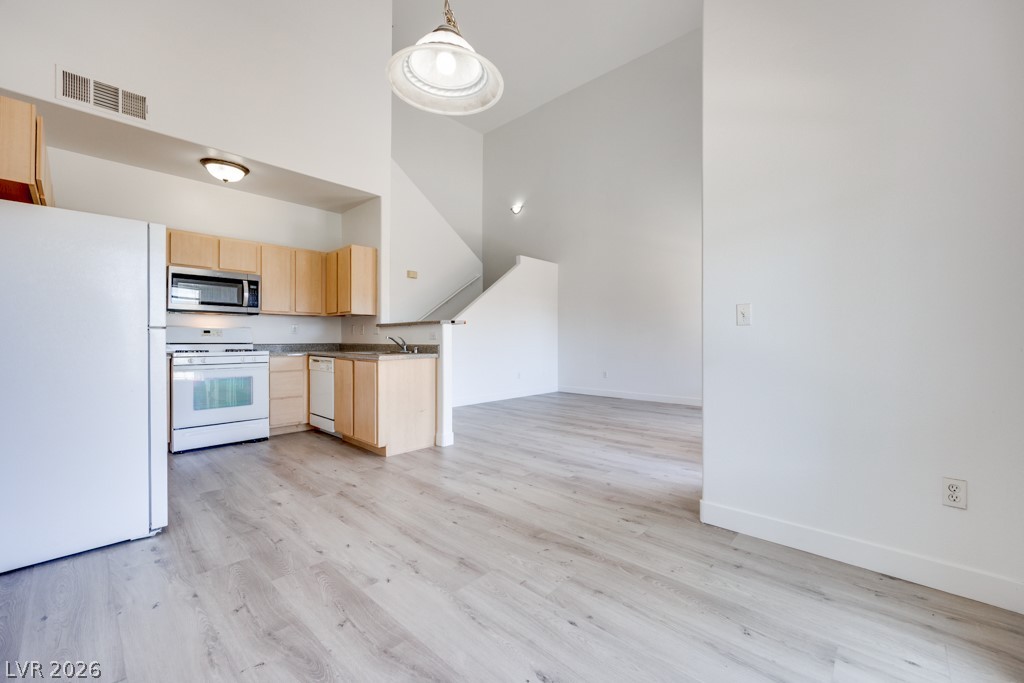 4915 East Russell Road, Unit 127 Las Vegas, NV 89120 - Photo 6 of 19 An open-concept living area features a well-appointed kitchen and convenient access to a staircase, all set against high ceilings.