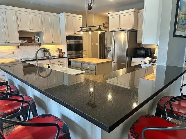 a kitchen with stainless steel appliances granite countertop a sink refrigerator and cabinets