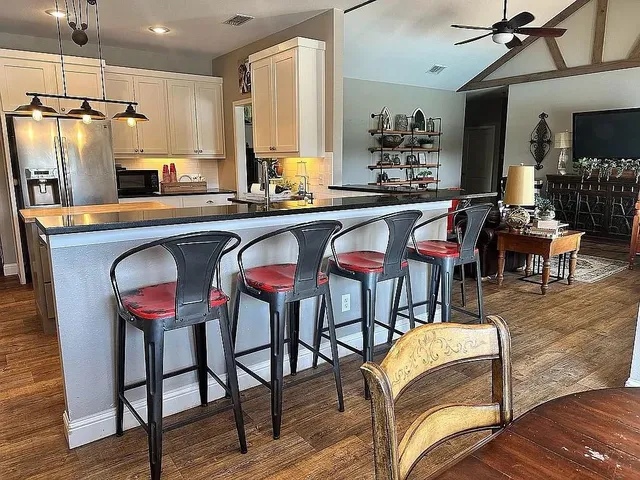 a dining hall with stainless steel appliances granite countertop a dining table and chairs with wooden floor