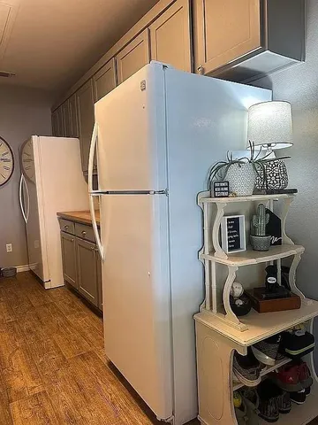 a kitchen with a refrigerator a stove and wooden floor