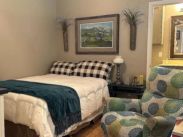 a bedroom with a bed two couch and a window