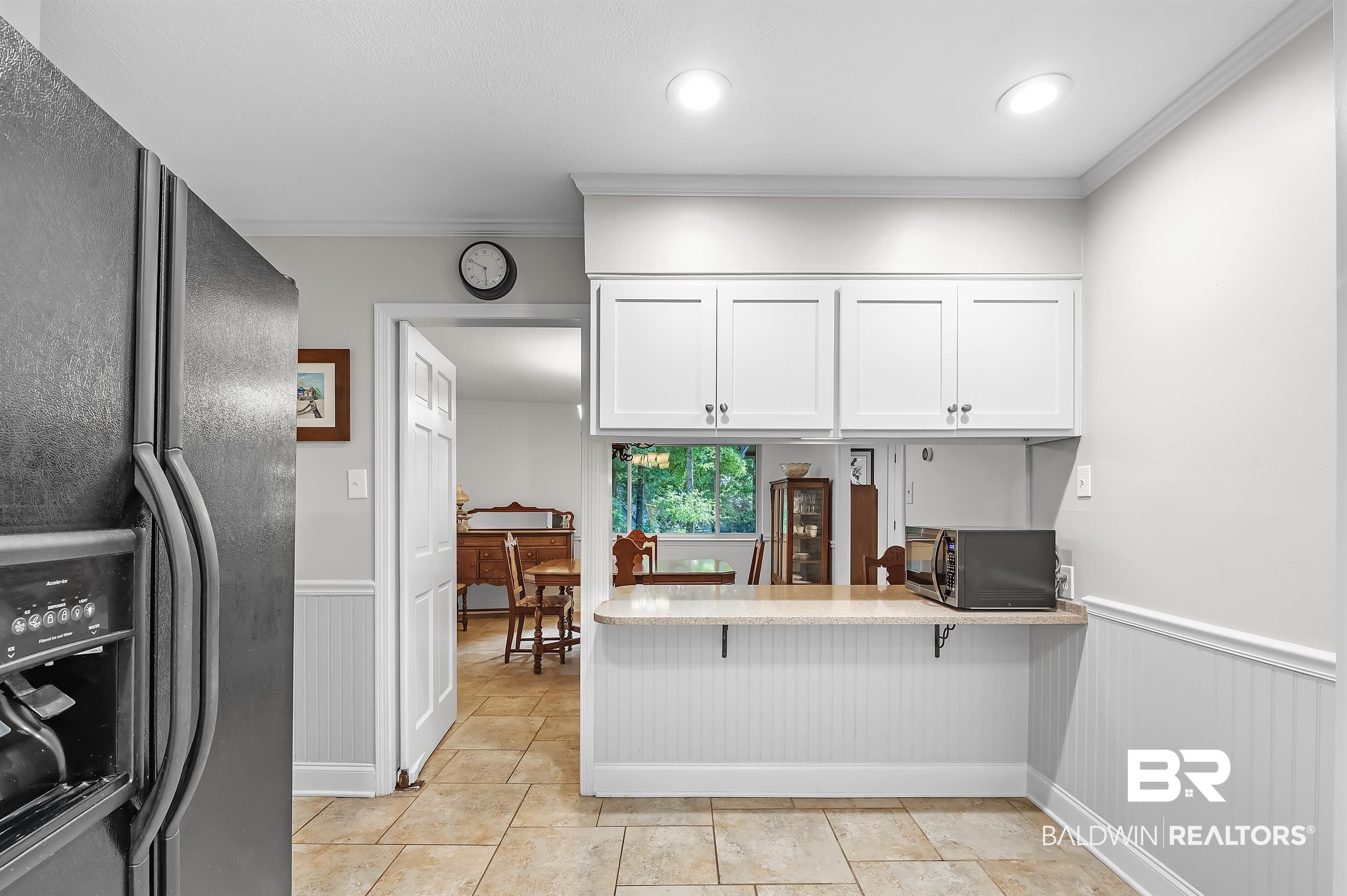 104 James Circle Daphne, AL 36526 - Photo 16 of 62 Kitchen with white cabinets, crown molding, black fridge, and light tile patterned floors