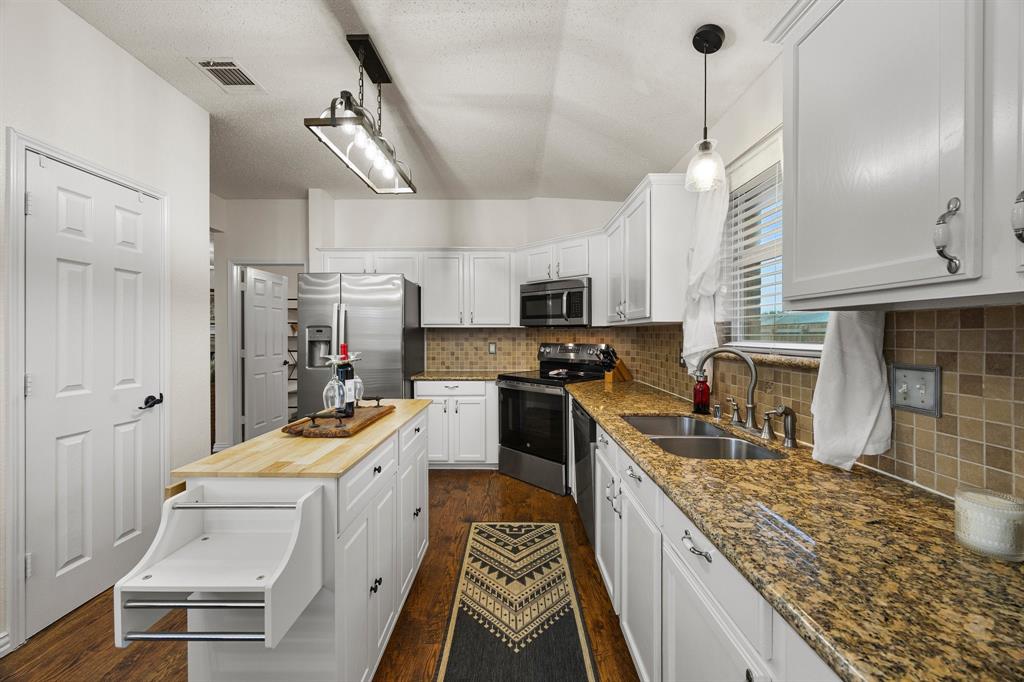 7210 Mercurys Road Rowlett, TX 75089 - Photo 6 of 26 a kitchen with stainless steel appliances kitchen island granite countertop a sink stove and refrigerator