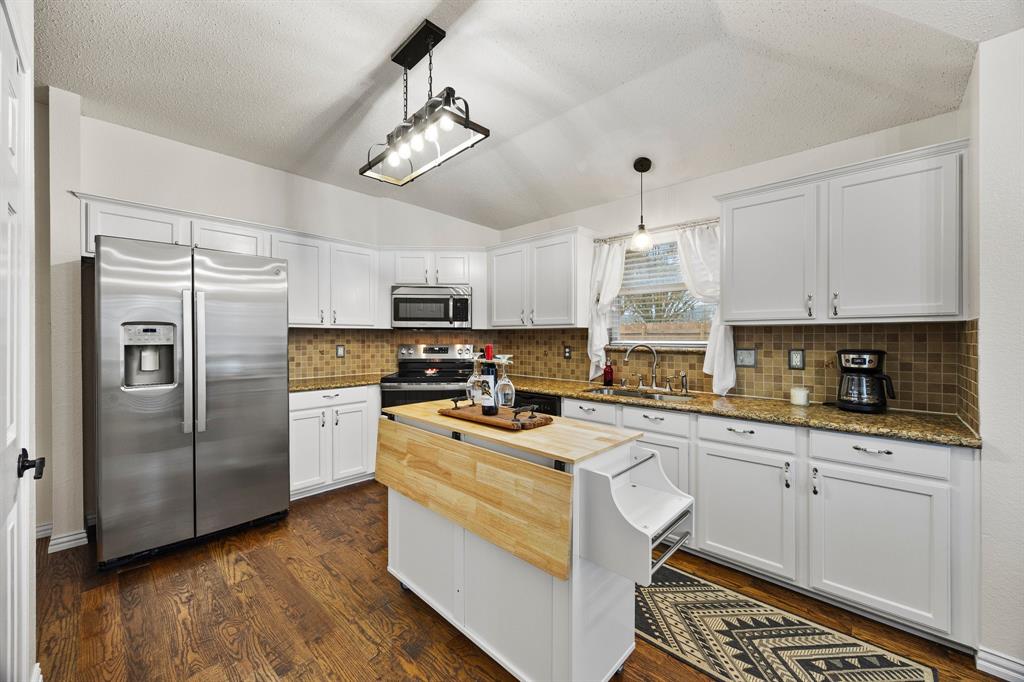7210 Mercurys Road Rowlett, TX 75089 - Photo 7 of 26 a kitchen with stainless steel appliances a stove a sink dishwasher a refrigerator white cabinets and wooden floor