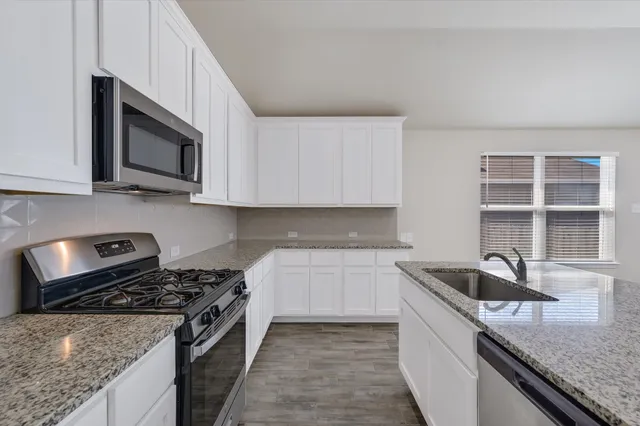 a kitchen with stainless steel appliances granite countertop a sink stove and microwave