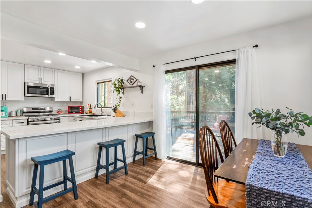 899 Blue Ridge Drive Lake Arrowhead, CA 92385 - Photo 7 of 49 a open kitchen with stainless steel appliances granite countertop a stove a refrigerator a kitchen island a table and chairs in it