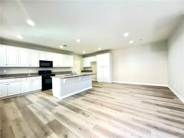 a large kitchen with granite countertop a large counter top stainless steel appliances and cabinets