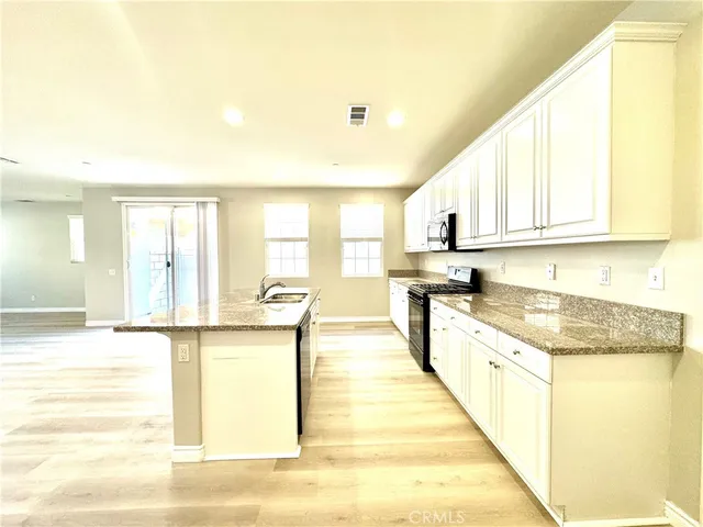 a large kitchen with stainless steel appliances granite countertop a sink and cabinets with wooden floor