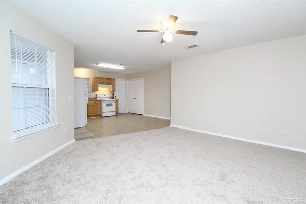 an empty room with chandelier fan and windows