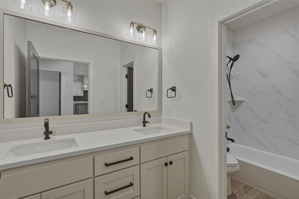 421 Red Bud Lane Tolar, TX 76476 - Photo 31 of 40 a bathroom with a double vanity sink a mirror and a bathtub