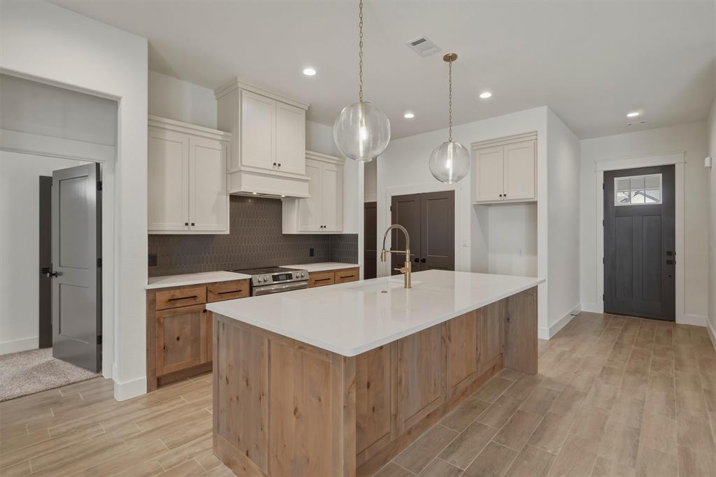 421 Red Bud Lane Tolar, TX 76476 - Photo 10 of 40 a large kitchen with kitchen island a stove a sink a refrigerator and white cabinets with wooden floor