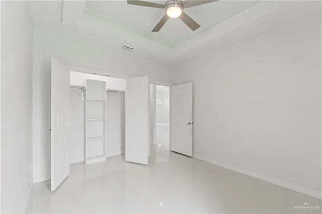 a view of an empty room and chandelier fan