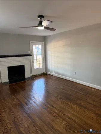 a view of an empty room with wooden floor and a fireplace