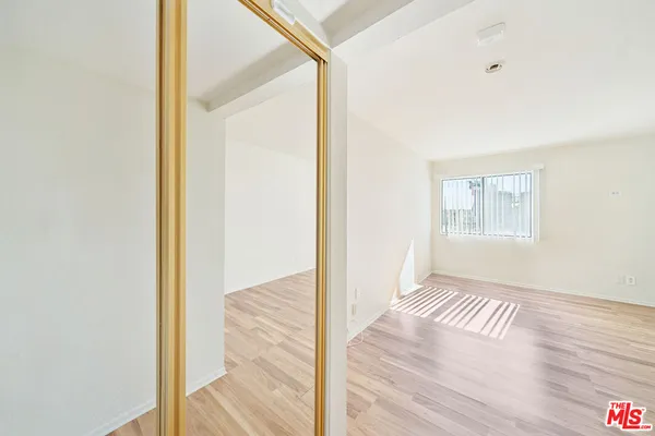 a view of an empty room with wooden floor and a window