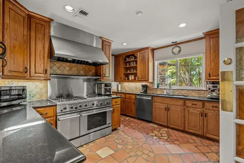 a kitchen with stainless steel appliances granite countertop a stove sink and cabinets