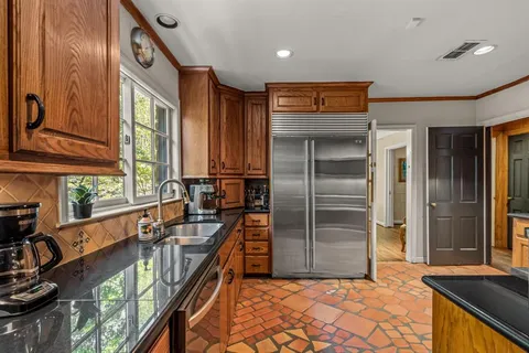 a kitchen with stainless steel appliances granite countertop a refrigerator a stove and a sink with large window