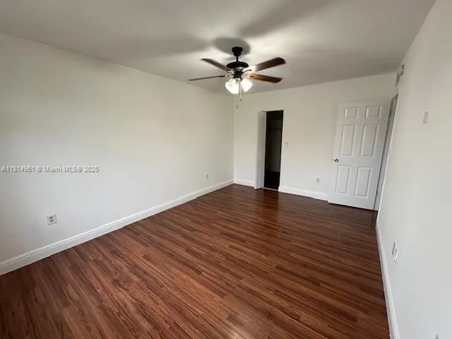 a view of a room with wooden floor and a ceiling fan