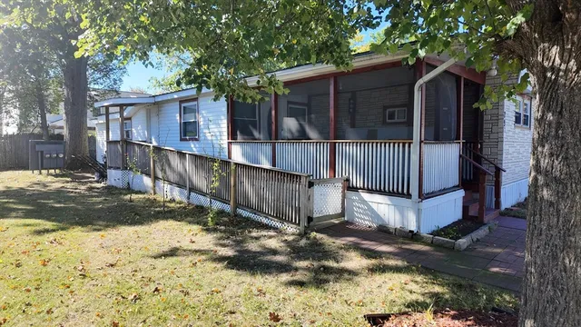 a view of a house with a large tree and wooden fence