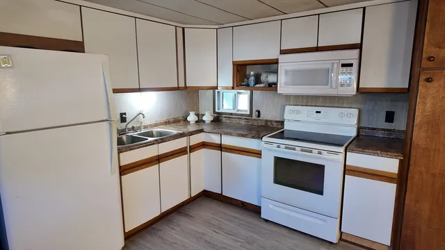 a kitchen with granite countertop white cabinets and white appliances