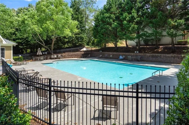 a view of a swimming pool with a patio and wooden fence