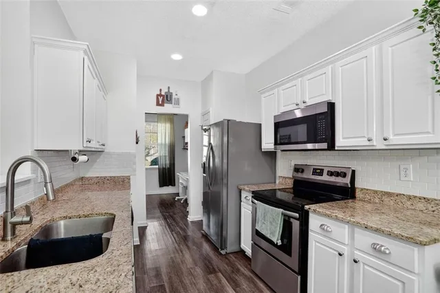 a kitchen with stainless steel appliances kitchen island granite countertop a stove a sink and a refrigerator